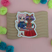 A photo of a sticker. The art is by Ayumutan Art, and depicts anthropomorphic cat characters inspired by the anime Utena