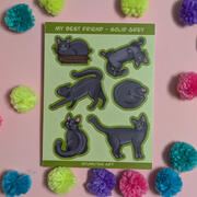 A picture of a sticker sheet featuring artwork of a grey cat in different poses on a green background
